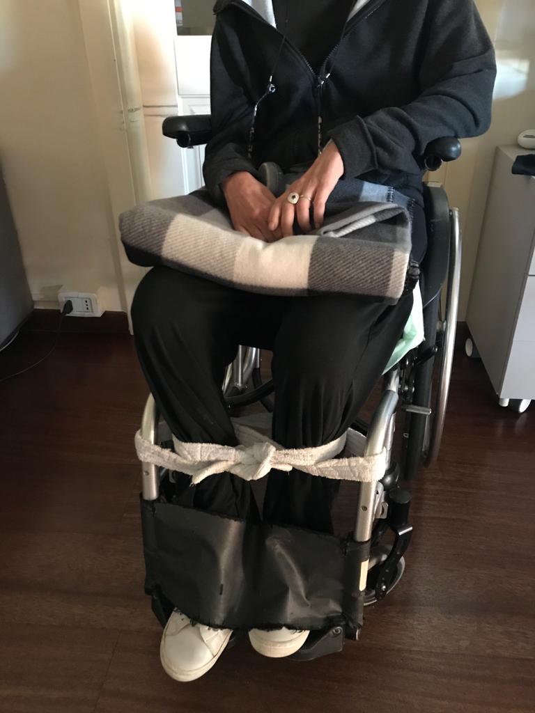 In foto Francesca (nome di fantasia) costretta a farsi legare le gambe per evitare che gli spasmi dovuti alla sclerosi multipla la facciano cadere a terra